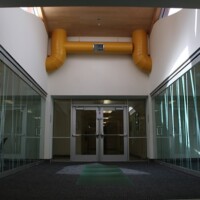 A view of the hallway with a classroom on either side. Each classroom is private, yet open with the bamboo etched glass walls and doors.